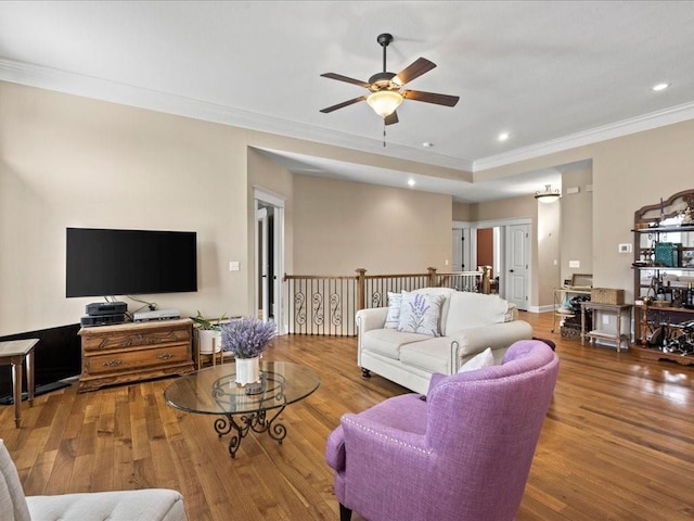 living room with crown molding, wood-type flooring, and ceiling fan