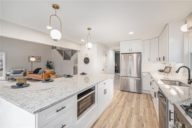 kitchen with decorative light fixtures, white cabinetry, sink, and appliances with stainless steel finishes