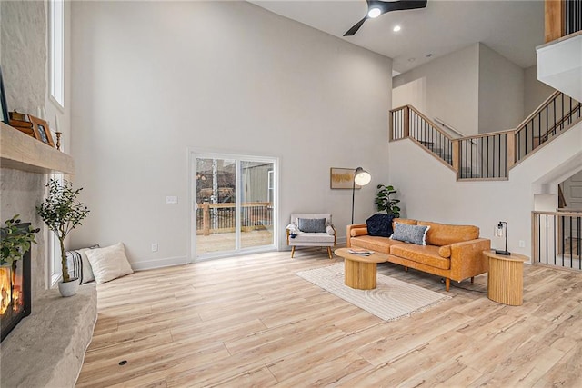 living room with a high ceiling, light hardwood / wood-style flooring, ceiling fan, and a healthy amount of sunlight