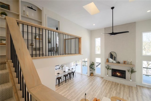 living room with a large fireplace, ceiling fan, and light hardwood / wood-style flooring