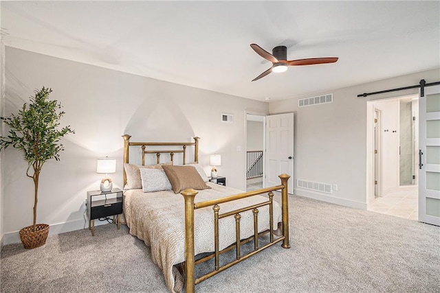 carpeted bedroom featuring ceiling fan, a barn door, and ensuite bath