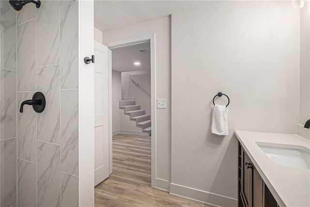 bathroom featuring tiled shower, hardwood / wood-style floors, vanity, and a textured ceiling