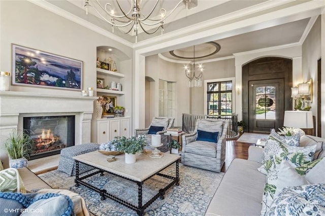 living room featuring ornamental molding, a chandelier, built in features, and light wood-type flooring