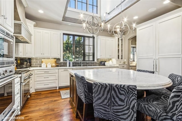 kitchen featuring a breakfast bar area, white cabinetry, light stone counters, a center island, and appliances with stainless steel finishes