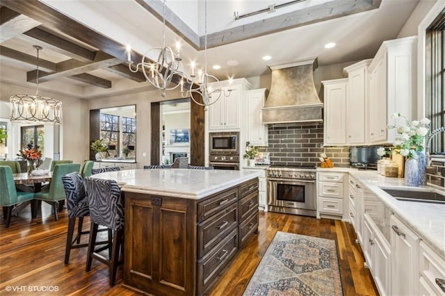 kitchen with custom exhaust hood, an inviting chandelier, white cabinetry, appliances with stainless steel finishes, and a kitchen island