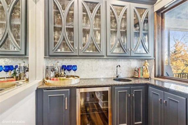 bar featuring sink, dark stone countertops, wine cooler, and decorative backsplash