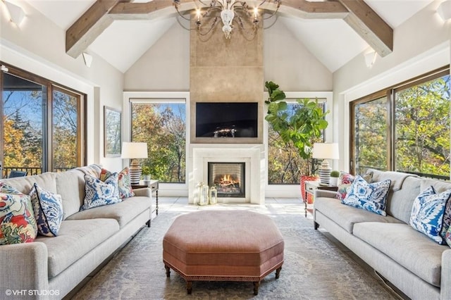 living room featuring beamed ceiling, plenty of natural light, a fireplace, and an inviting chandelier