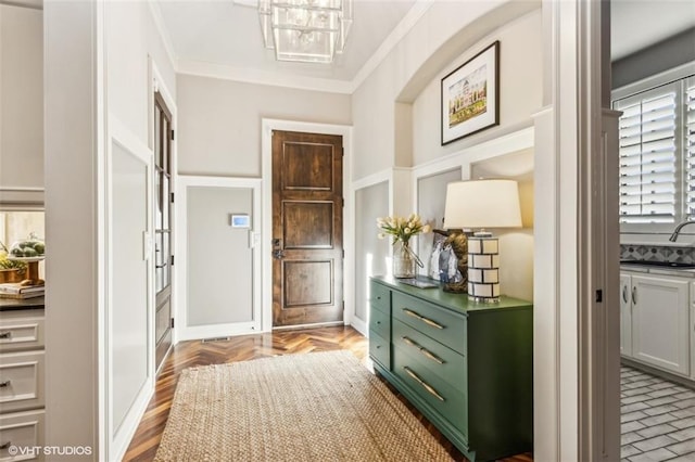 doorway with crown molding, a chandelier, and light parquet floors