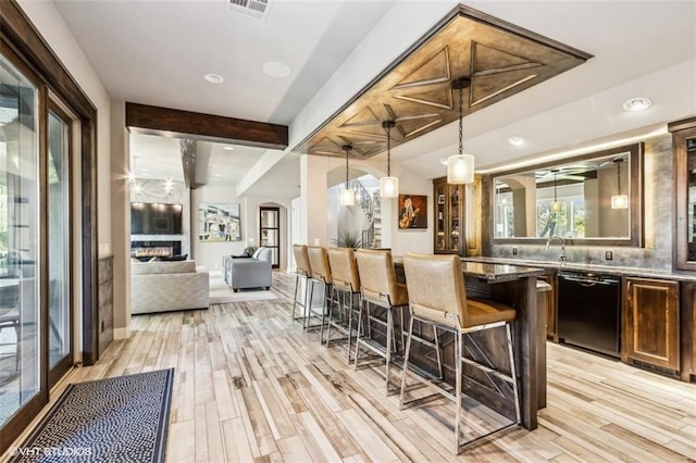 bar with pendant lighting, beam ceiling, black dishwasher, and light wood-type flooring