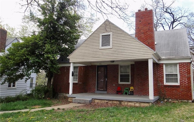 rear view of property with covered porch and a yard