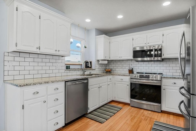 kitchen featuring tasteful backsplash, stainless steel appliances, sink, light hardwood / wood-style flooring, and white cabinetry