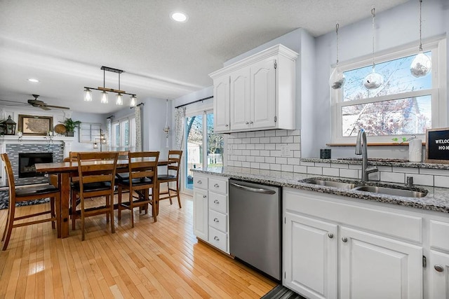 kitchen with white cabinetry, sink, ceiling fan, stainless steel dishwasher, and pendant lighting