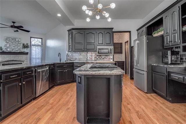 kitchen featuring sink, tasteful backsplash, dark stone countertops, a kitchen island, and appliances with stainless steel finishes