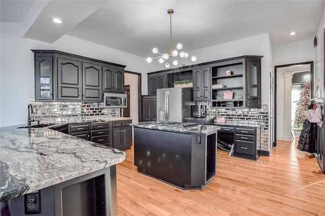 kitchen with sink, hanging light fixtures, tasteful backsplash, stone countertops, and stainless steel appliances