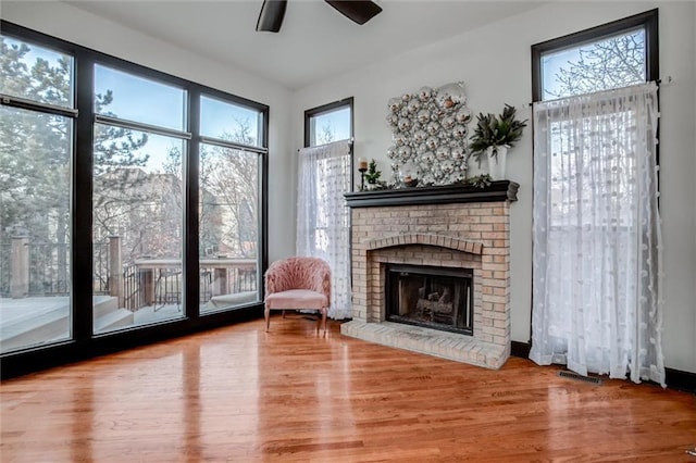 living area with a fireplace, hardwood / wood-style floors, and ceiling fan