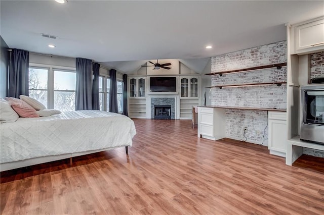 unfurnished bedroom featuring light hardwood / wood-style flooring, vaulted ceiling, and brick wall