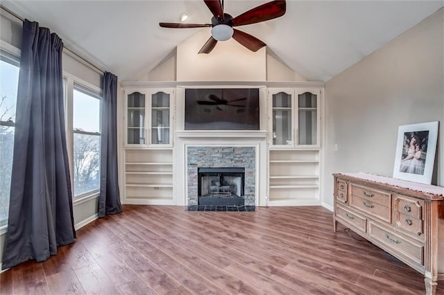 unfurnished living room featuring vaulted ceiling, a stone fireplace, and dark wood-type flooring