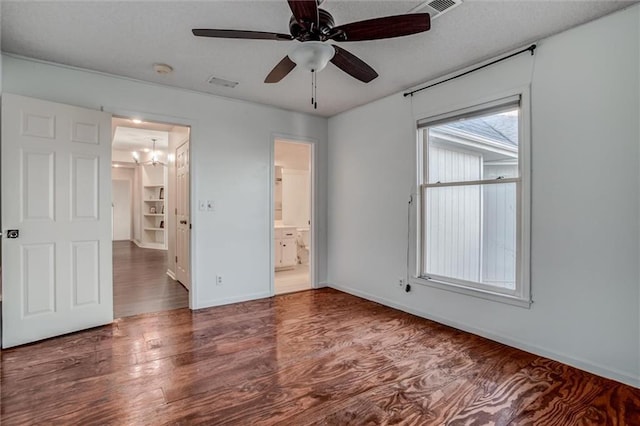 unfurnished bedroom featuring ceiling fan with notable chandelier, dark hardwood / wood-style flooring, and ensuite bathroom