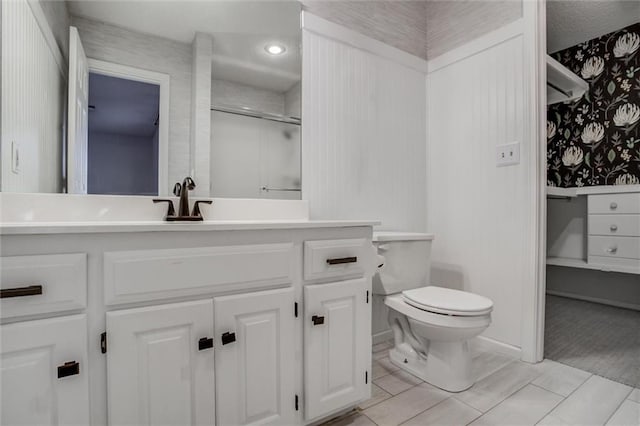 bathroom featuring vanity, toilet, and a shower with door