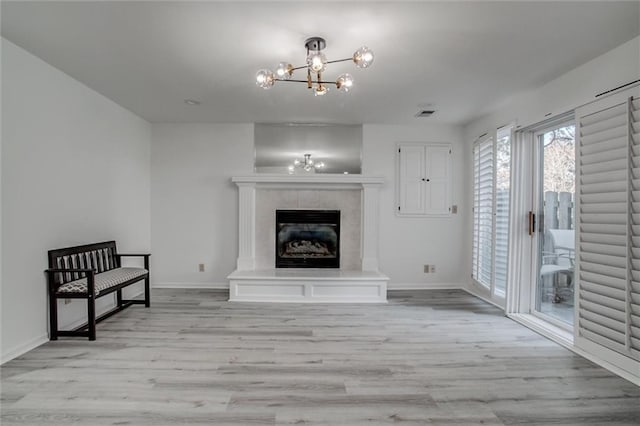 living room featuring a fireplace, a chandelier, and light hardwood / wood-style flooring