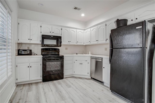 kitchen with light wood-type flooring, backsplash, sink, black appliances, and white cabinets