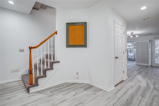 stairway with hardwood / wood-style flooring and an inviting chandelier