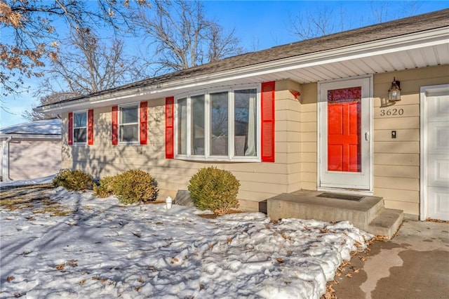 snow covered property entrance with a garage