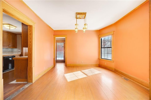 empty room featuring light wood-type flooring, crown molding, and baseboards