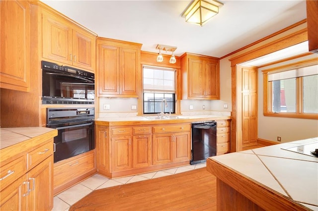 kitchen with tile counters, light tile patterned flooring, a sink, and black appliances