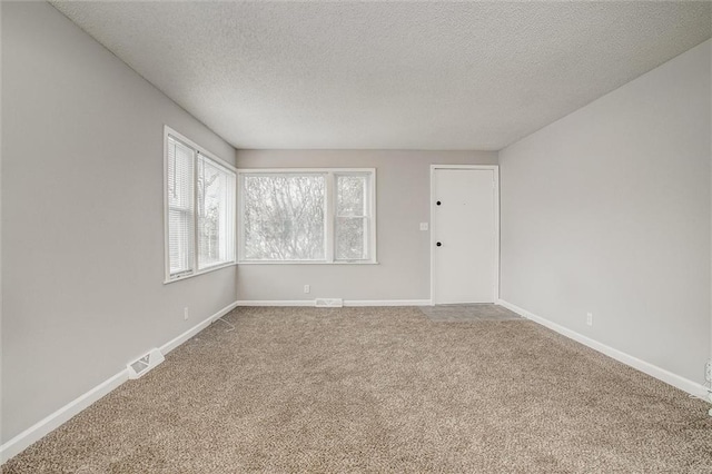 carpeted empty room with a textured ceiling