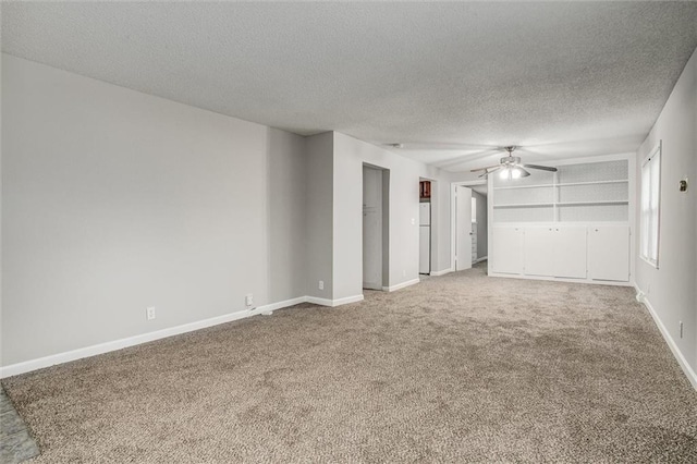 empty room with carpet flooring, built in shelves, ceiling fan, and a textured ceiling