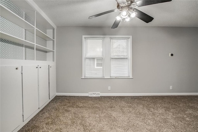 carpeted spare room featuring ceiling fan, built in features, and a textured ceiling