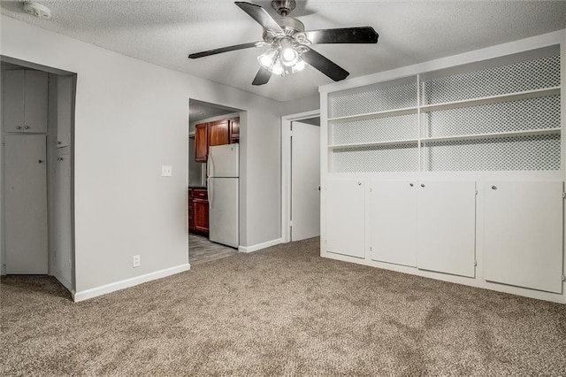 unfurnished bedroom with a textured ceiling, white fridge, ceiling fan, and light colored carpet