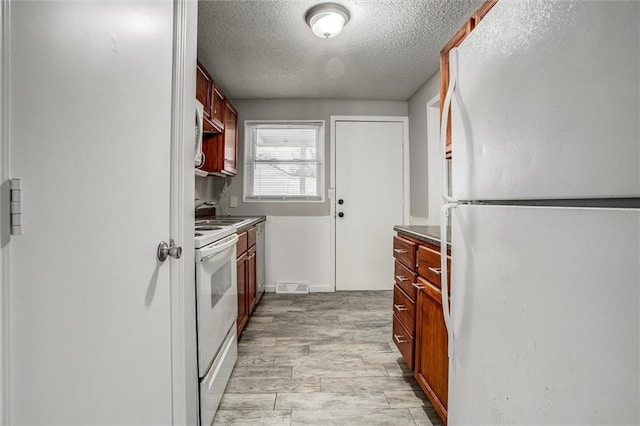 kitchen with a textured ceiling, light hardwood / wood-style flooring, and white appliances