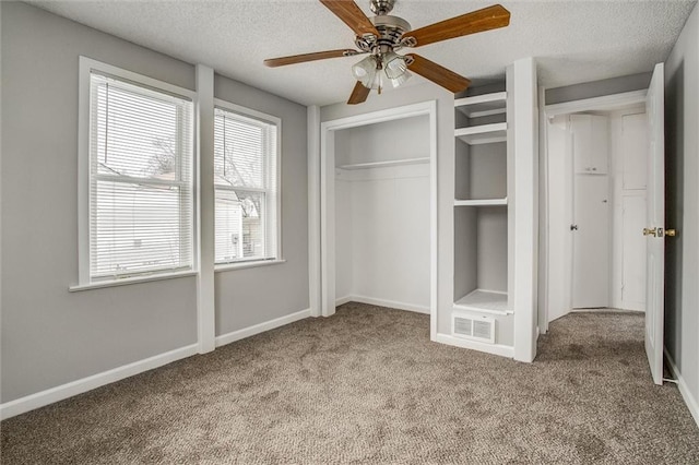 unfurnished bedroom with multiple windows, a textured ceiling, light colored carpet, and ceiling fan