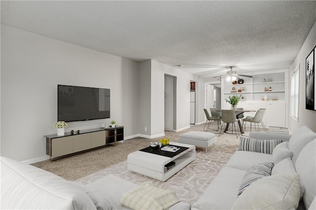 living room with ceiling fan, built in features, and a textured ceiling