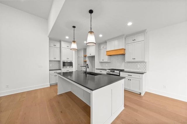 kitchen with dark countertops, baseboards, a sink, appliances with stainless steel finishes, and backsplash