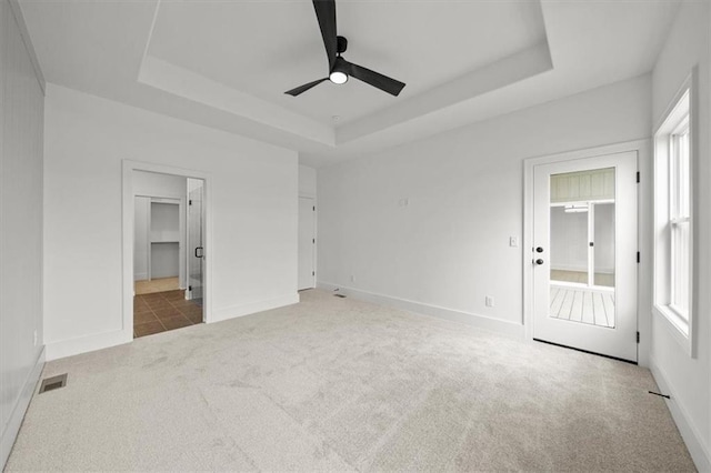 unfurnished bedroom with carpet floors, visible vents, ensuite bathroom, baseboards, and a raised ceiling