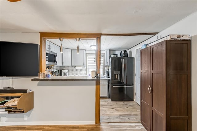 kitchen featuring decorative backsplash, stainless steel appliances, light hardwood / wood-style flooring, white cabinets, and hanging light fixtures