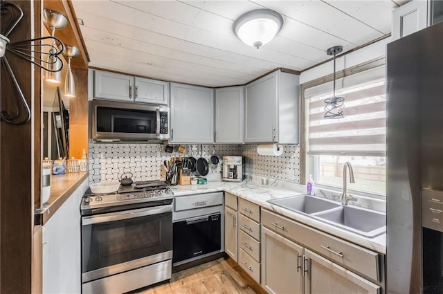 kitchen featuring gray cabinetry, sink, pendant lighting, decorative backsplash, and appliances with stainless steel finishes