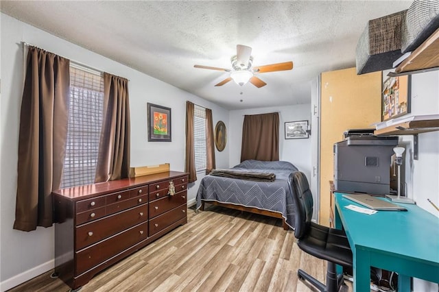 bedroom featuring ceiling fan, light hardwood / wood-style floors, and a textured ceiling