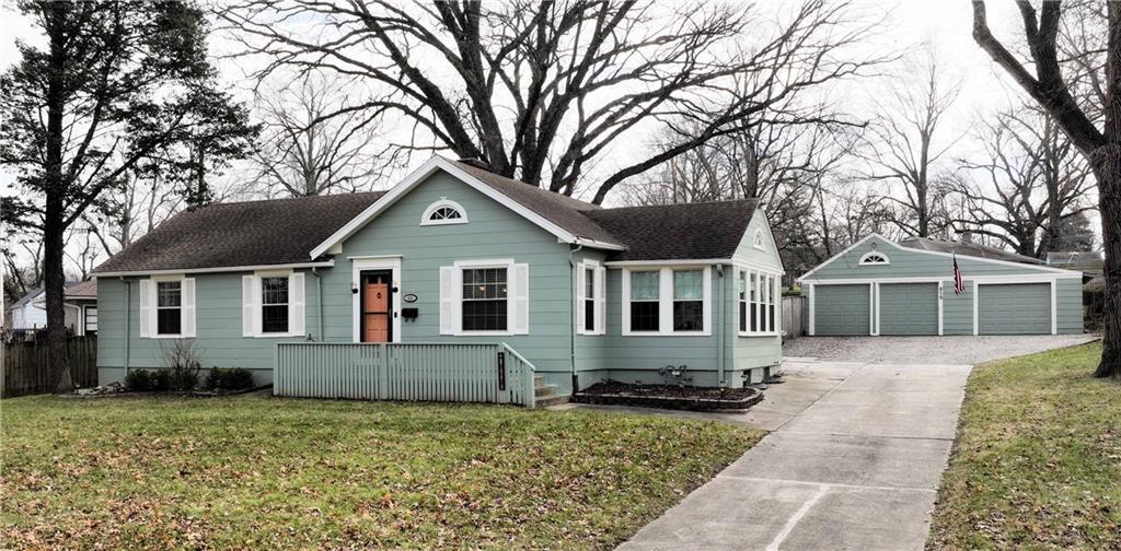 view of front of property featuring a front lawn, a garage, and an outbuilding