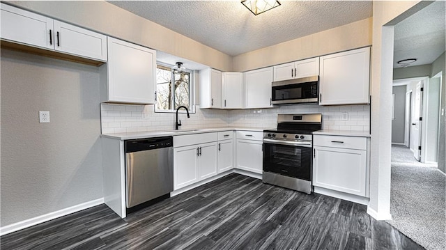 kitchen featuring dark carpet, sink, a textured ceiling, appliances with stainless steel finishes, and white cabinetry