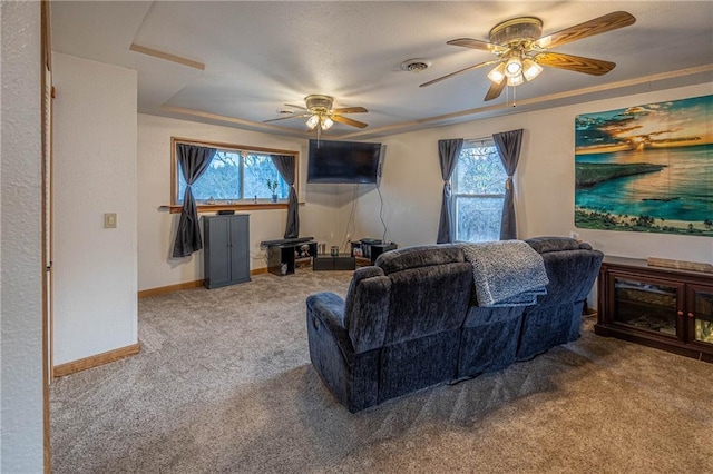 carpeted living room with a wealth of natural light, a tray ceiling, and ceiling fan