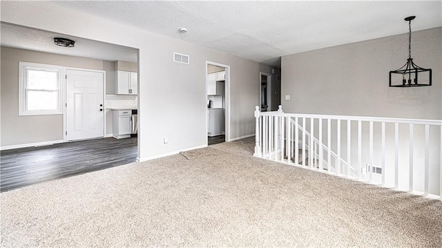 unfurnished room featuring dark carpet and a textured ceiling