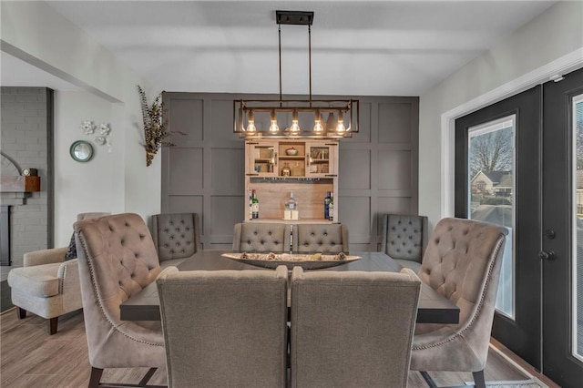 dining space featuring french doors, wood-type flooring, and a fireplace