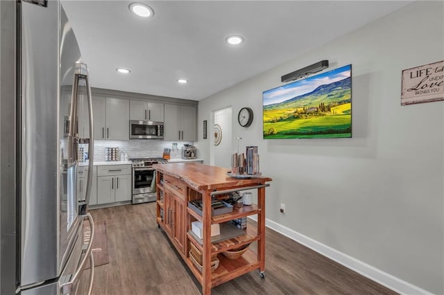 kitchen featuring stainless steel appliances, tasteful backsplash, dark wood-type flooring, and gray cabinetry