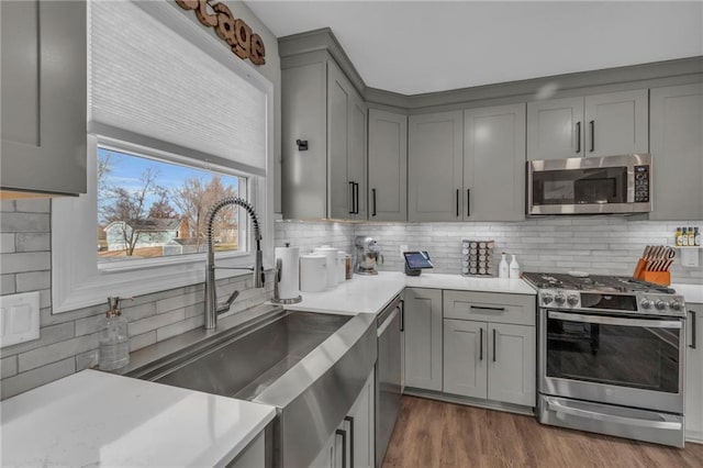 kitchen with sink, decorative backsplash, gray cabinets, and appliances with stainless steel finishes