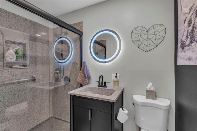 bathroom featuring vanity, toilet, and a shower with door