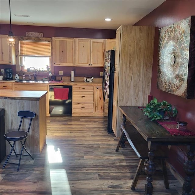 kitchen featuring light brown cabinetry, sink, decorative light fixtures, and black appliances